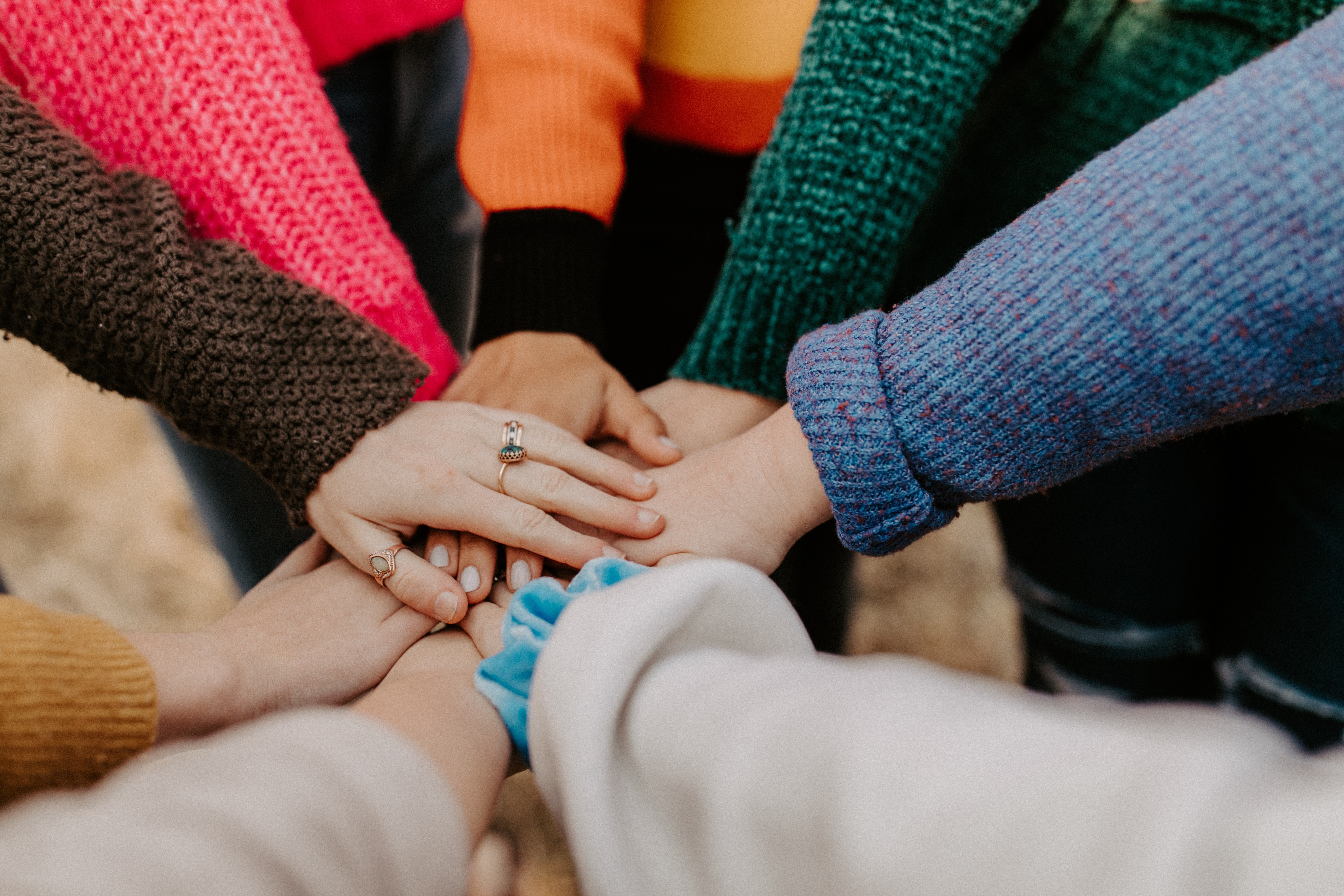 a close up of a diverse group of individuals forming a huddle with their hands meeting in the center